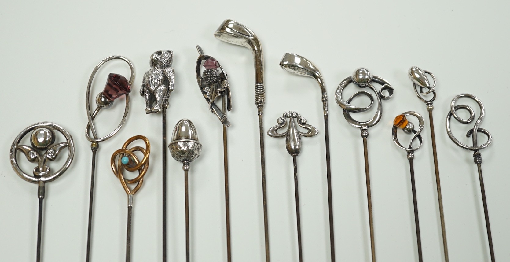 A collection of thirteen assorted early 20th century and later white or yellow metal hat pins, including four by Charles Horner including teddy bear and two silver golf club, longest 31.5cm.